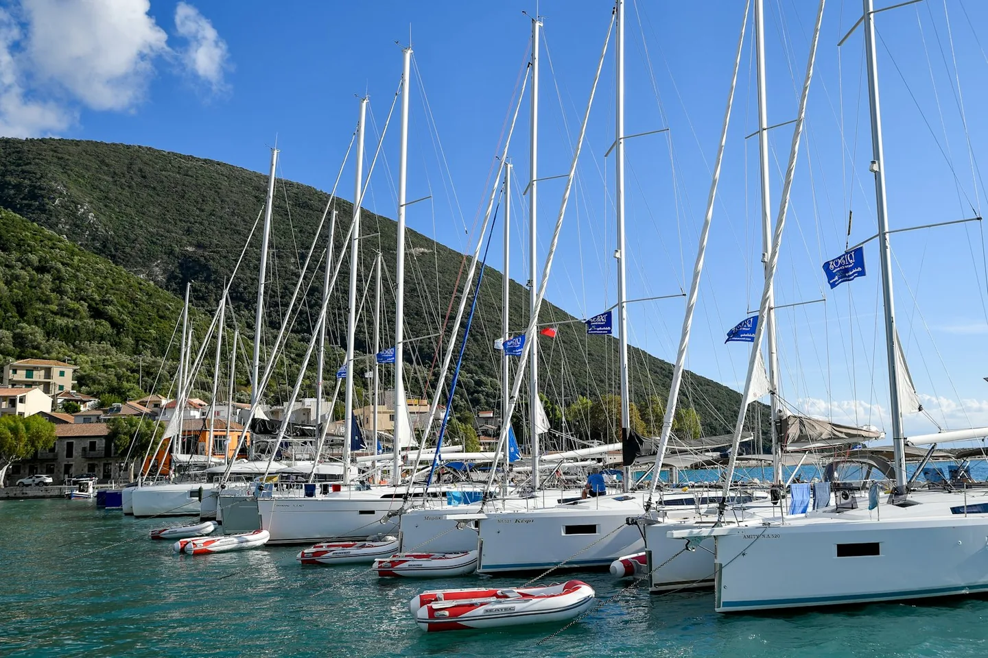 Velers amarrats en una marina mediterrània amb les muntanyes al fons